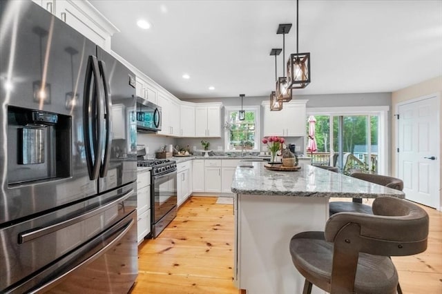 1085 Southbridge Rd, Warren, MA 01585 - kitchen featuring appliances with stainless steel finishes, light wood-type flooring, a kitchen breakfast bar, recessed lighting, and light stone counters
