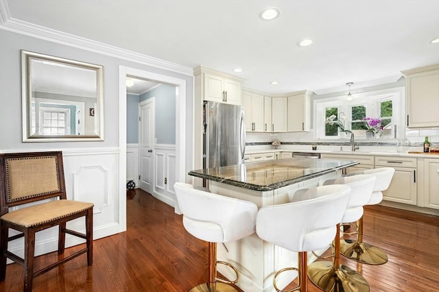 50 Depot St, Milford, MA 01757 - kitchen featuring appliances with stainless steel finishes, a breakfast bar, ornamental molding, a decorative wall, and dark stone countertops