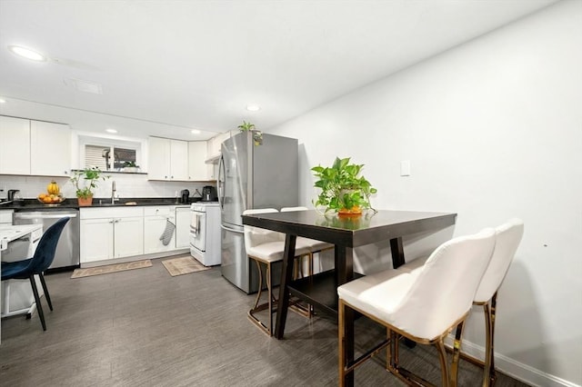 50 Depot St, Milford, MA 01757 - kitchen featuring stainless steel appliances, dark countertops, dark wood finished floors, recessed lighting, and tasteful backsplash