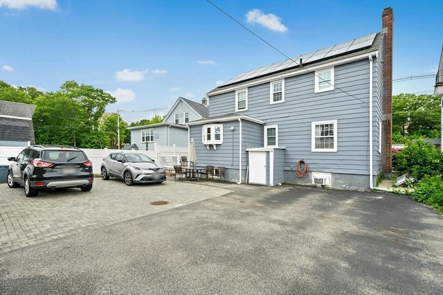 50 Depot St, Milford, MA 01757 - rear view of property with roof mounted solar panels, a chimney, and a patio