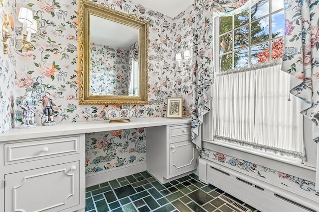bathroom featuring wallpapered walls, baseboard heating, vanity, baseboards, and brick patterned floors