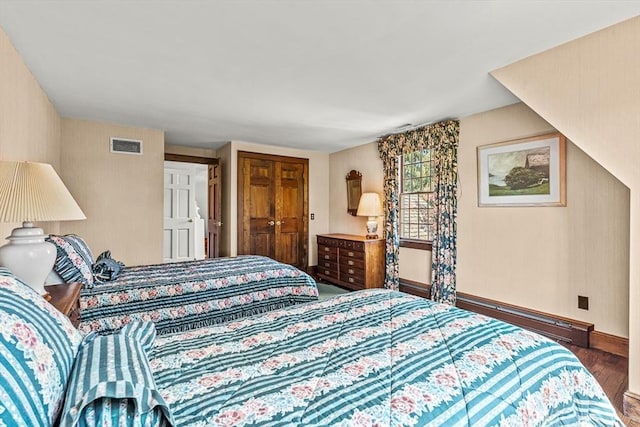 bedroom featuring wood finished floors, a baseboard radiator, baseboards, and a closet
