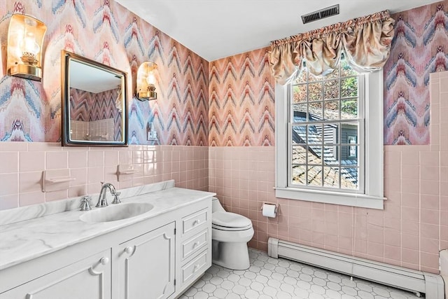 bathroom with baseboard heating, wallpapered walls, tile walls, toilet, and vanity