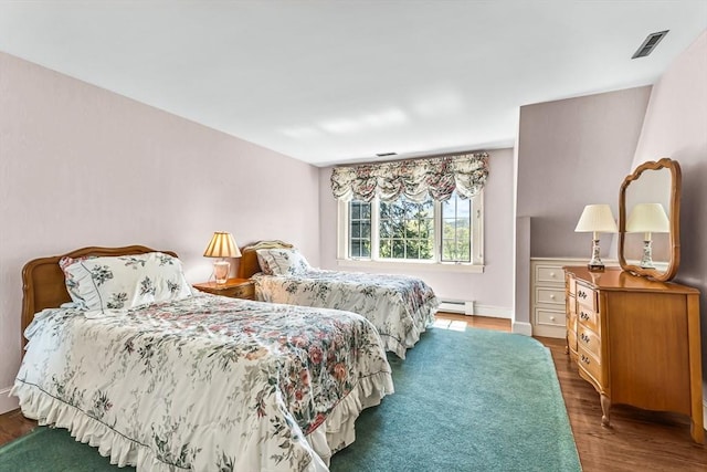 bedroom featuring baseboard heating and wood finished floors