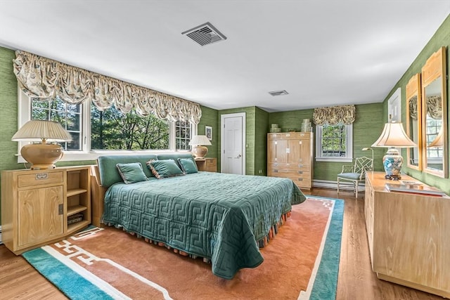 bedroom featuring wood finished floors and baseboard heating