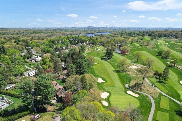 view of property location with a local golf course, a tree filled landscape, and a large body of water