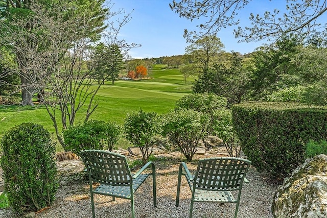 view of property's community with view of golf course and a lawn