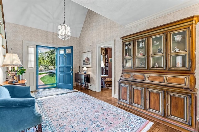foyer entrance featuring wallpapered walls, a chandelier, wood finished floors, lofted ceiling, and baseboards