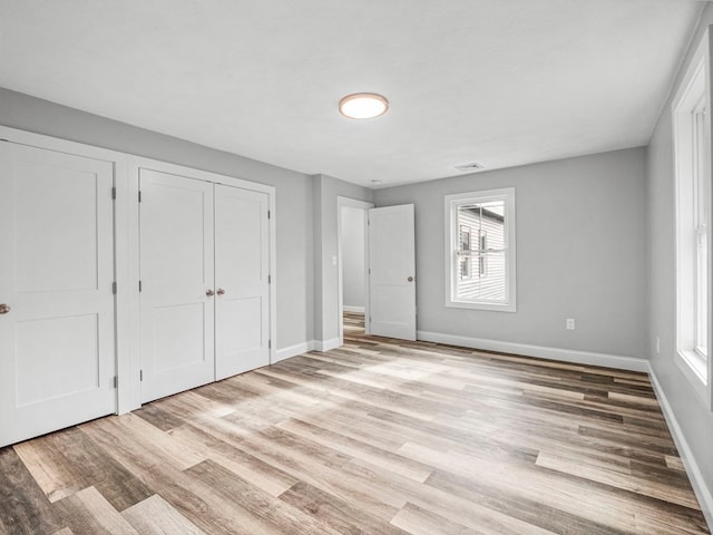 unfurnished bedroom with multiple windows, multiple closets, and light wood-type flooring