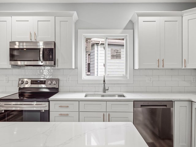 kitchen featuring backsplash, white cabinetry, sink, and appliances with stainless steel finishes