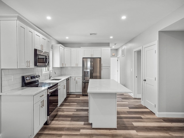 kitchen featuring sink, dark wood-type flooring, a kitchen island, white cabinets, and appliances with stainless steel finishes