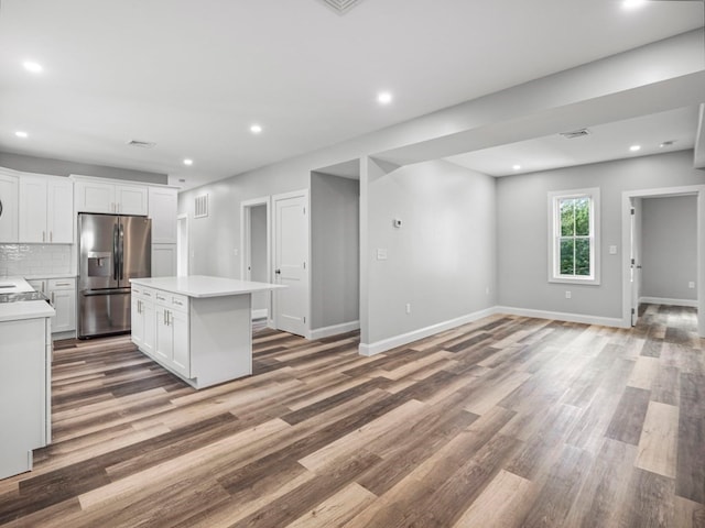 kitchen with white cabinets, a center island, stainless steel refrigerator with ice dispenser, and hardwood / wood-style floors