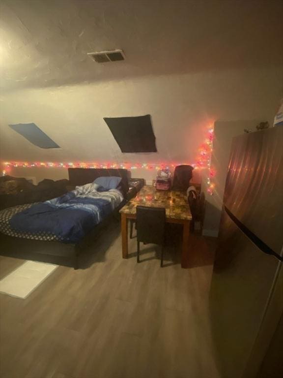 bedroom with stainless steel refrigerator and hardwood / wood-style flooring