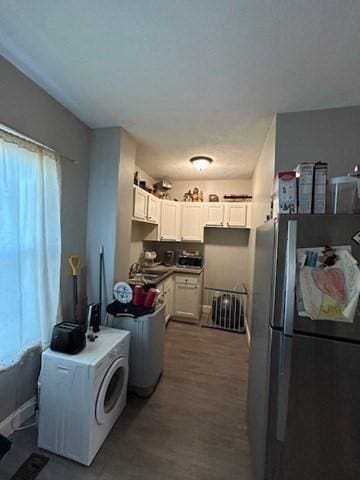 kitchen featuring black fridge, white cabinetry, and sink