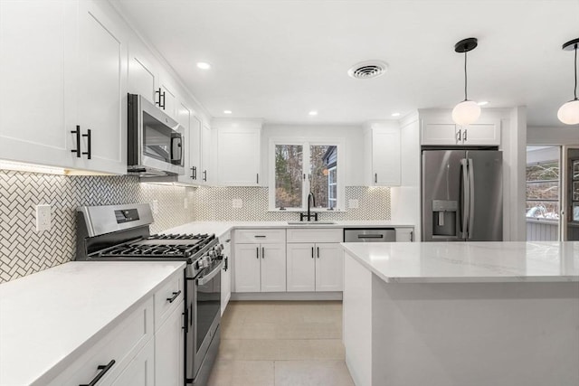 kitchen featuring hanging light fixtures, white cabinetry, appliances with stainless steel finishes, and sink