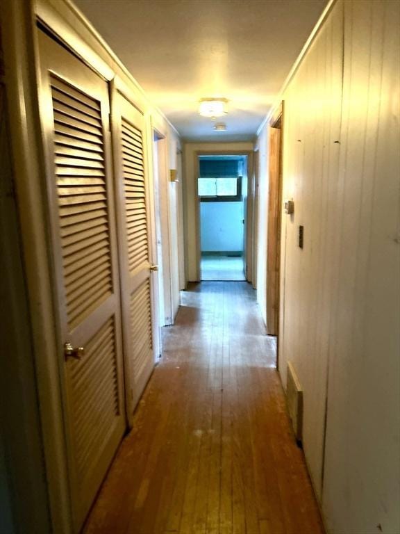 hallway with crown molding and light wood-type flooring