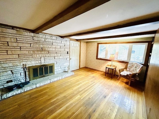 unfurnished room featuring hardwood / wood-style flooring, a fireplace, and beamed ceiling