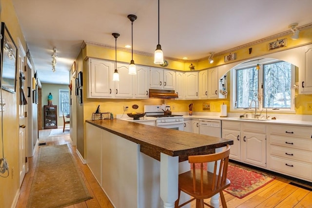 kitchen featuring white appliances, a breakfast bar, sink, and white cabinets