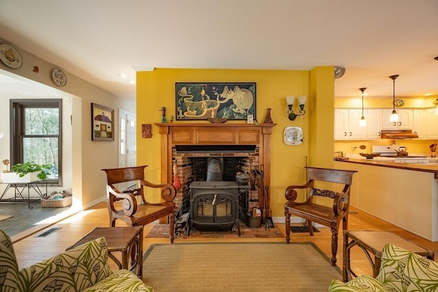 sitting room with a wood stove and light wood-type flooring