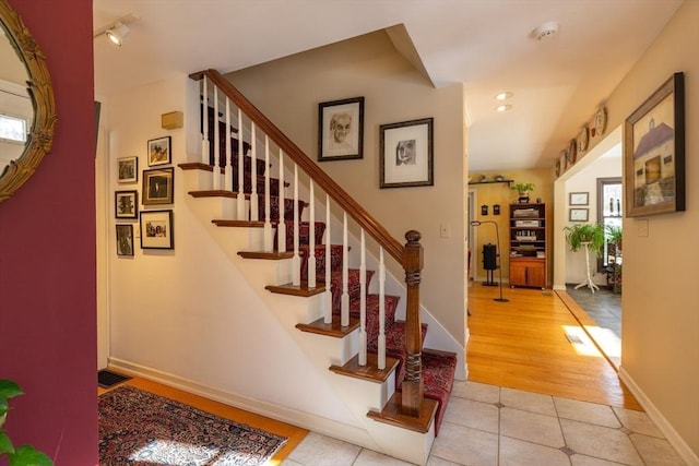 staircase featuring rail lighting and tile patterned flooring