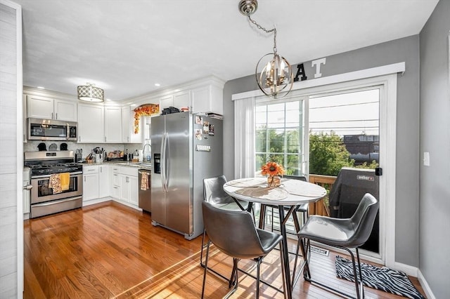 15 Alton St Unit 16, Lowell, MA 01852 - kitchen with appliances with stainless steel finishes, white cabinets, a sink, a chandelier, and decorative backsplash