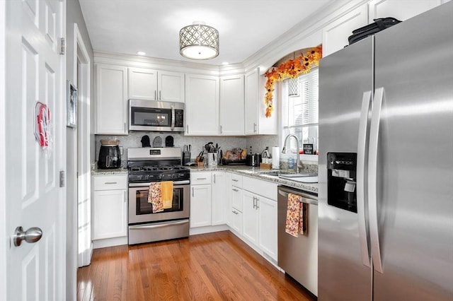 15 Alton St Unit 16, Lowell, MA 01852 - kitchen featuring stainless steel appliances, a sink, white cabinets, light stone countertops, and tasteful backsplash