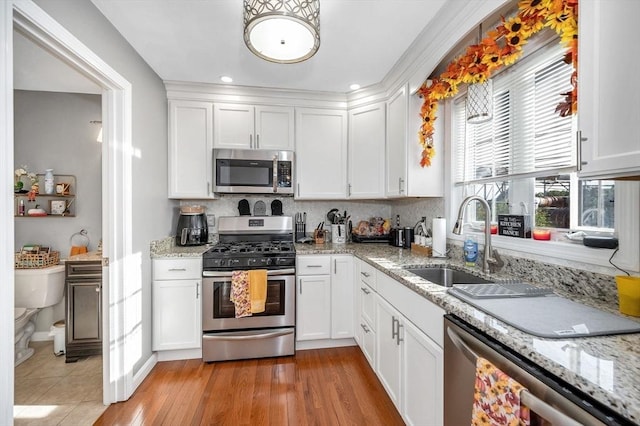 15 Alton St Unit 16, Lowell, MA 01852 - kitchen featuring appliances with stainless steel finishes, a sink, white cabinets, backsplash, and recessed lighting