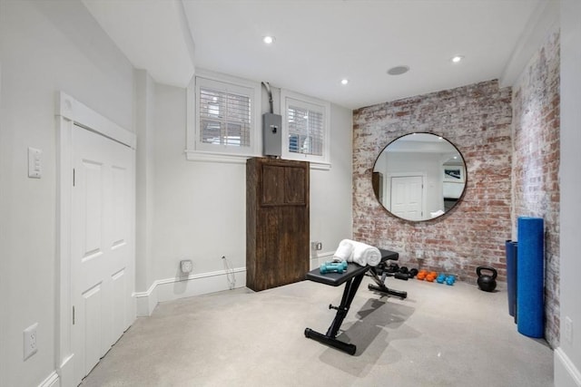 exercise room with brick wall and light colored carpet