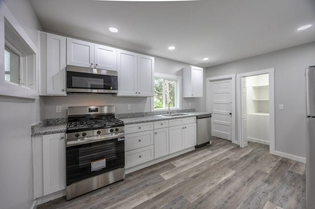 338-340 Main St, Fairhaven, MA 02719 - kitchen with stainless steel appliances, white cabinets, light wood finished floors, light stone counters, and recessed lighting
