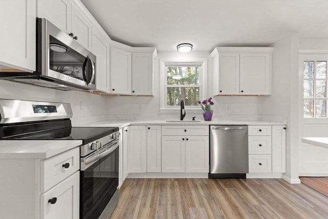 kitchen with stainless steel appliances, white cabinetry, plenty of natural light, and sink