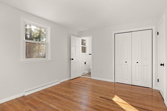 unfurnished bedroom with hardwood / wood-style flooring, a baseboard radiator, and a closet