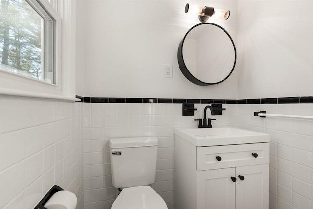 bathroom featuring vanity, tile walls, and toilet