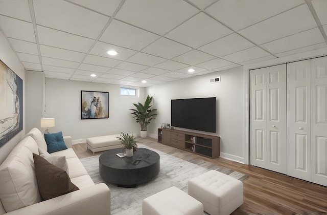 living room with wood-type flooring and a drop ceiling