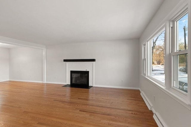 unfurnished living room featuring wood-type flooring and baseboard heating