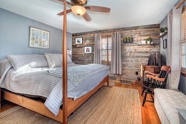 bedroom featuring wooden walls, light hardwood / wood-style floors, and ceiling fan