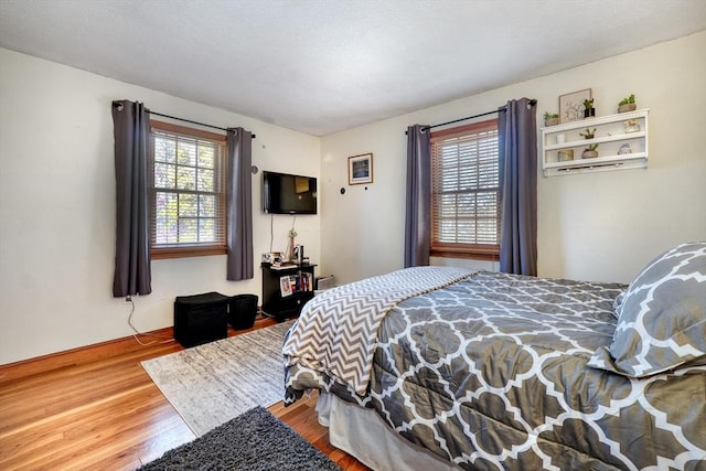 bedroom with multiple windows and hardwood / wood-style flooring