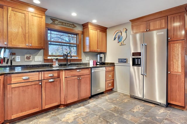 kitchen featuring stainless steel appliances, sink, and dark stone countertops