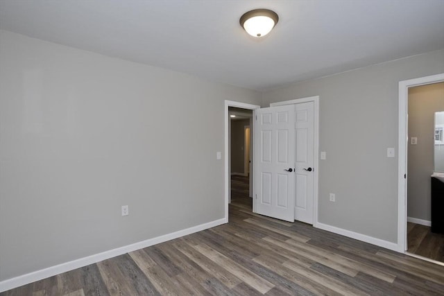 unfurnished bedroom with dark hardwood / wood-style flooring and a closet