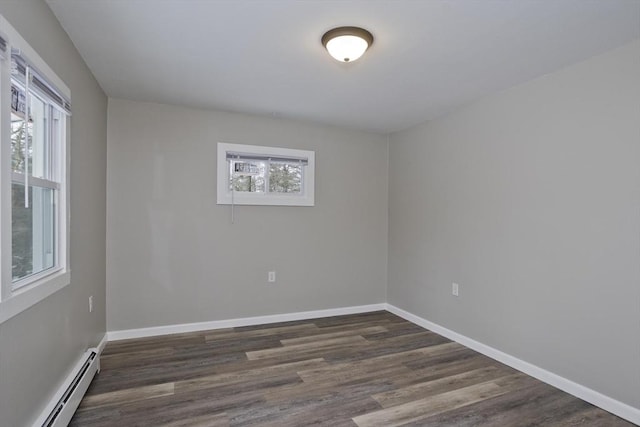 empty room with a healthy amount of sunlight, a baseboard heating unit, and dark wood-type flooring