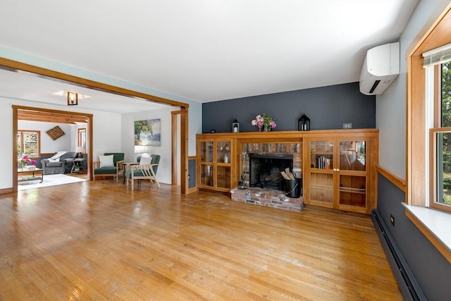 6 Paddock Dr, Harwich, MA 02645 - living area featuring a baseboard radiator, a wall mounted air conditioner, light wood-style flooring, and a fireplace