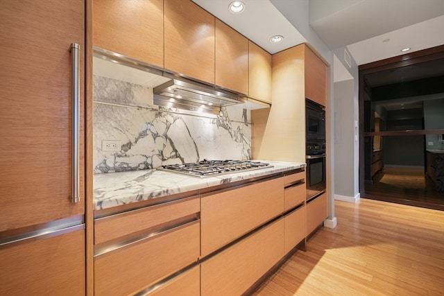 kitchen featuring black appliances, backsplash, and light wood-type flooring