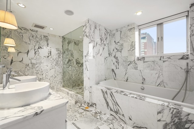 bathroom with independent shower and bath, double sink vanity, and tile walls