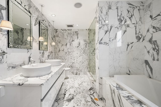 bathroom with tiled tub, tile floors, tile walls, oversized vanity, and dual sinks