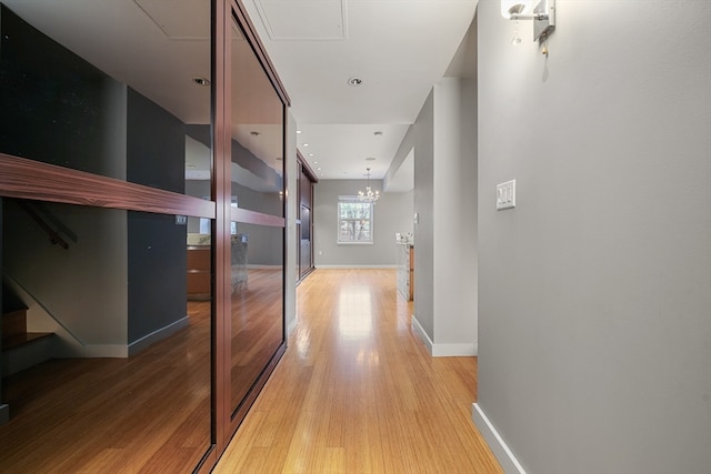 hallway featuring a notable chandelier and light hardwood / wood-style flooring