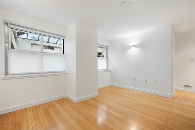 unfurnished room with a healthy amount of sunlight and light hardwood / wood-style floors