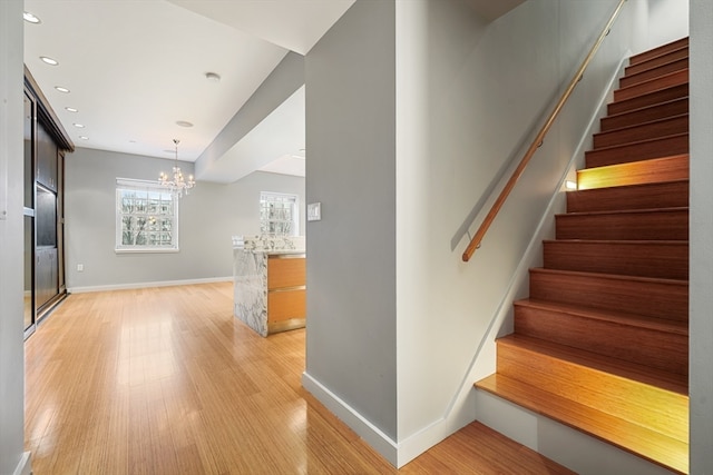 stairway with a chandelier and light hardwood / wood-style flooring