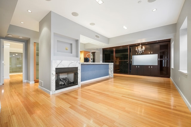 unfurnished living room featuring a notable chandelier, light hardwood / wood-style floors, and a fireplace