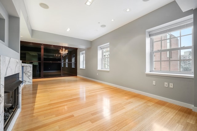 unfurnished living room with light wood-type flooring, plenty of natural light, and a fireplace