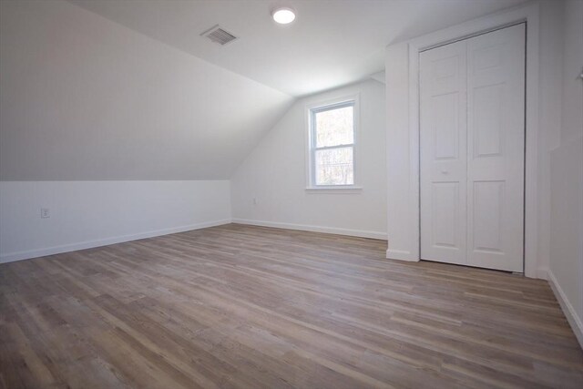 additional living space with vaulted ceiling and light wood-type flooring