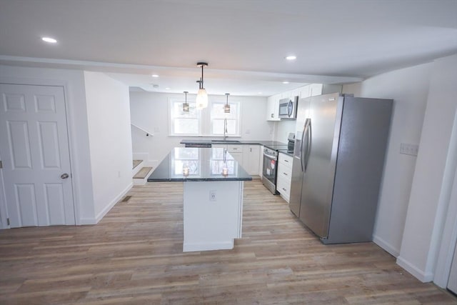 kitchen featuring sink, hanging light fixtures, appliances with stainless steel finishes, a kitchen island, and white cabinets